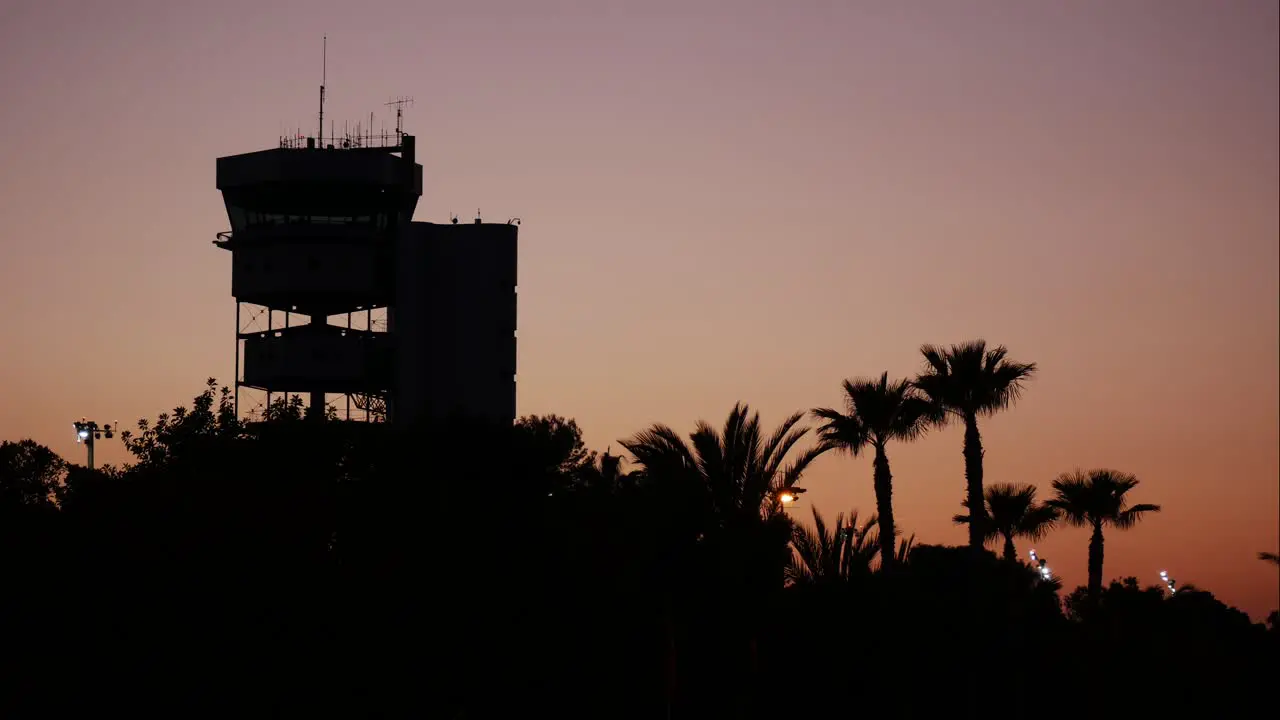 Aircraft control tower at a tropical airport during a golden sunset time lapse