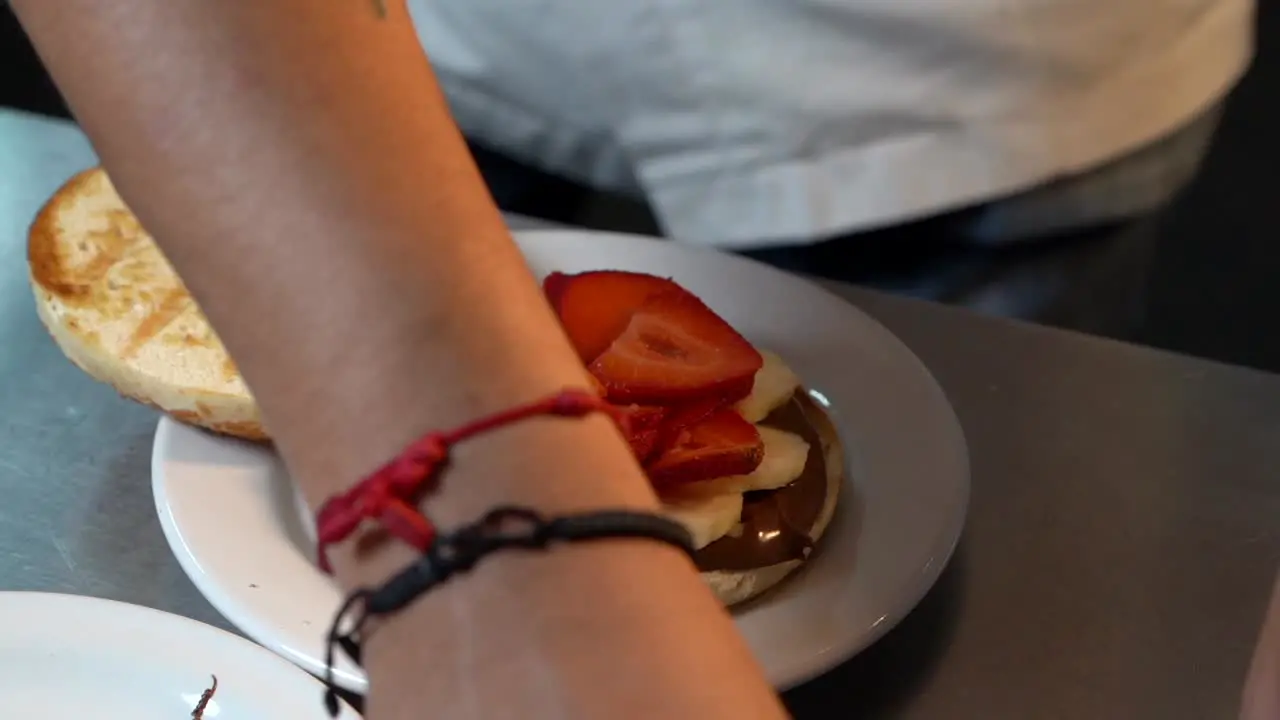 Chef preparing toast bagel with hazelnut cream banana and berries strawberries