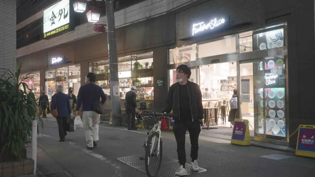 Man With Mask Under Chin Walking With Bike On The Street Of Jiyugaoka During Pandemic In Tokyo Japan