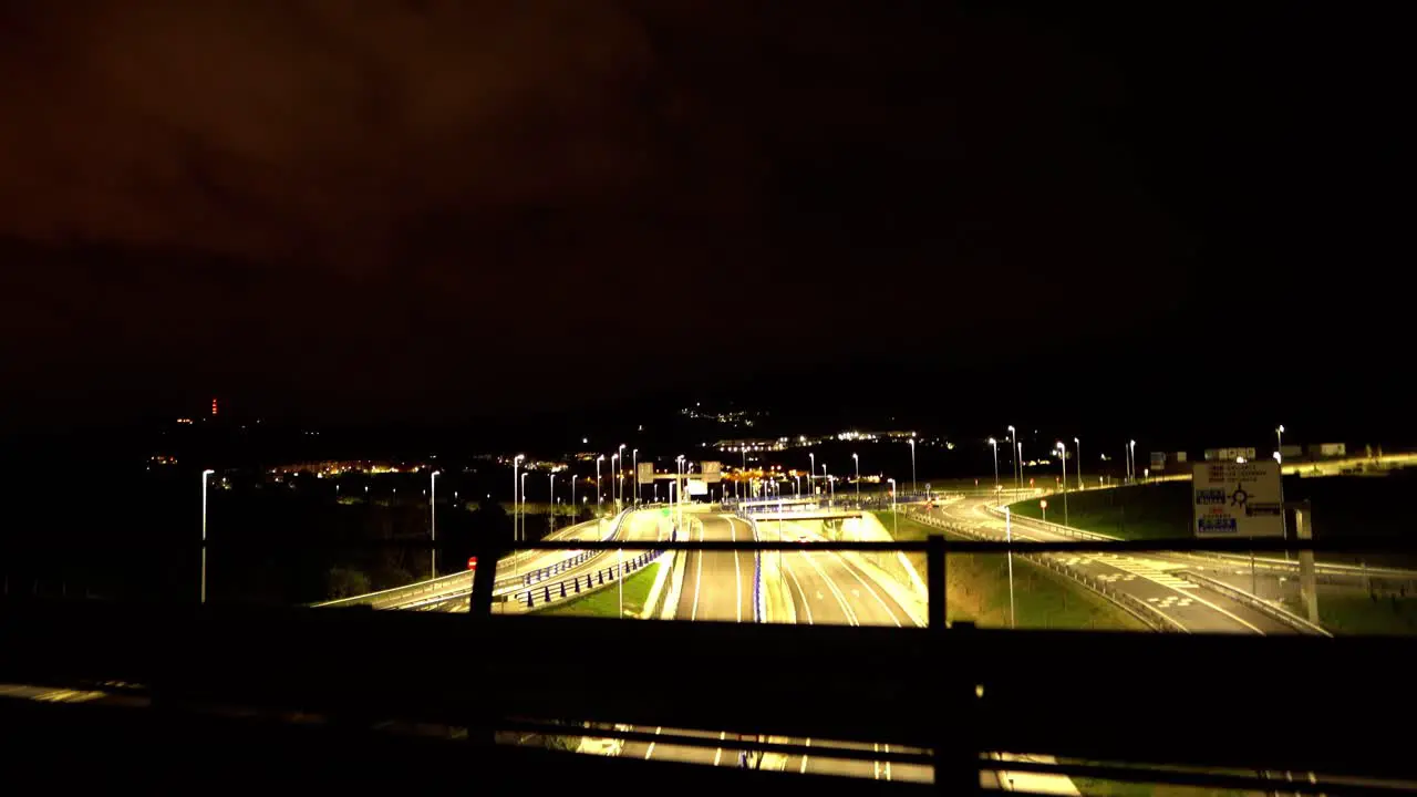 Cars driving by on lit up highway at night aerial freeway bridge view