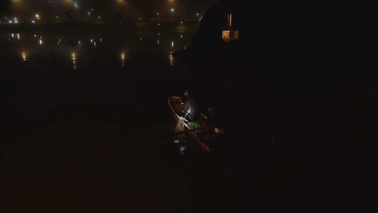 Two fishermen on their boat with one of them pulling in a fishing net