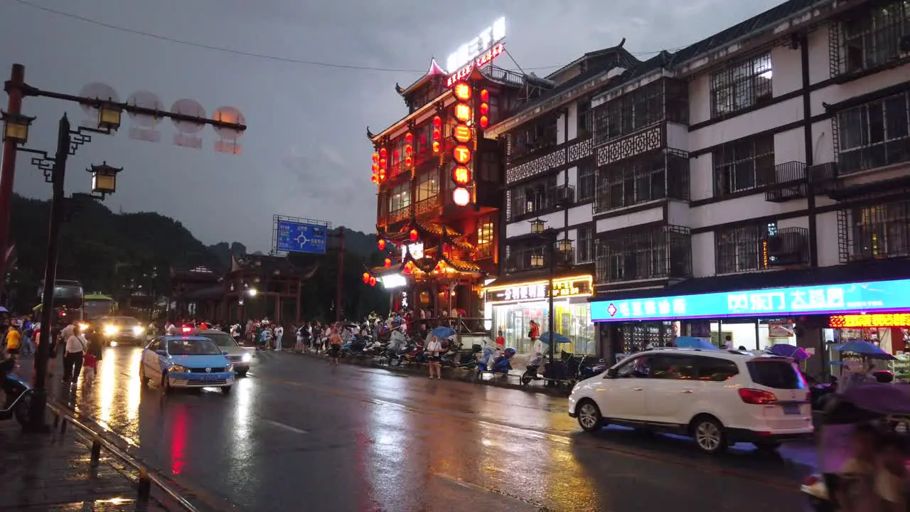 Wulingyuan China August 2019  Bustling life with cars traffic and lights on buildings lit at night at a busy high street in town at dusk