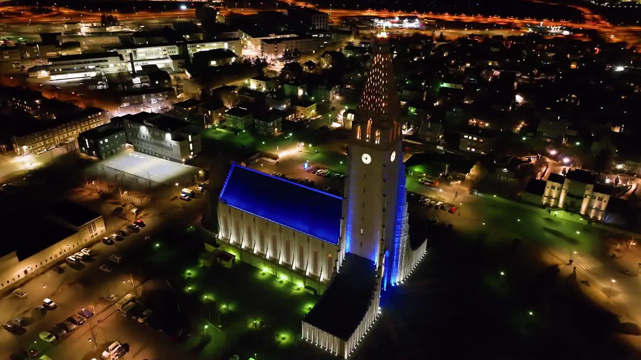 Drone shot circling the night lit Hallgrímskirkja church in Reykjavik Iceland