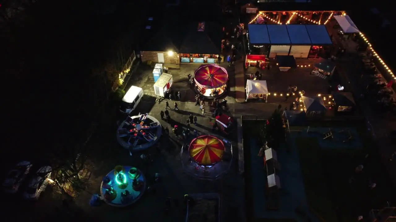 Illuminated Christmas amusement park in neighbourhood car park at night aerial view