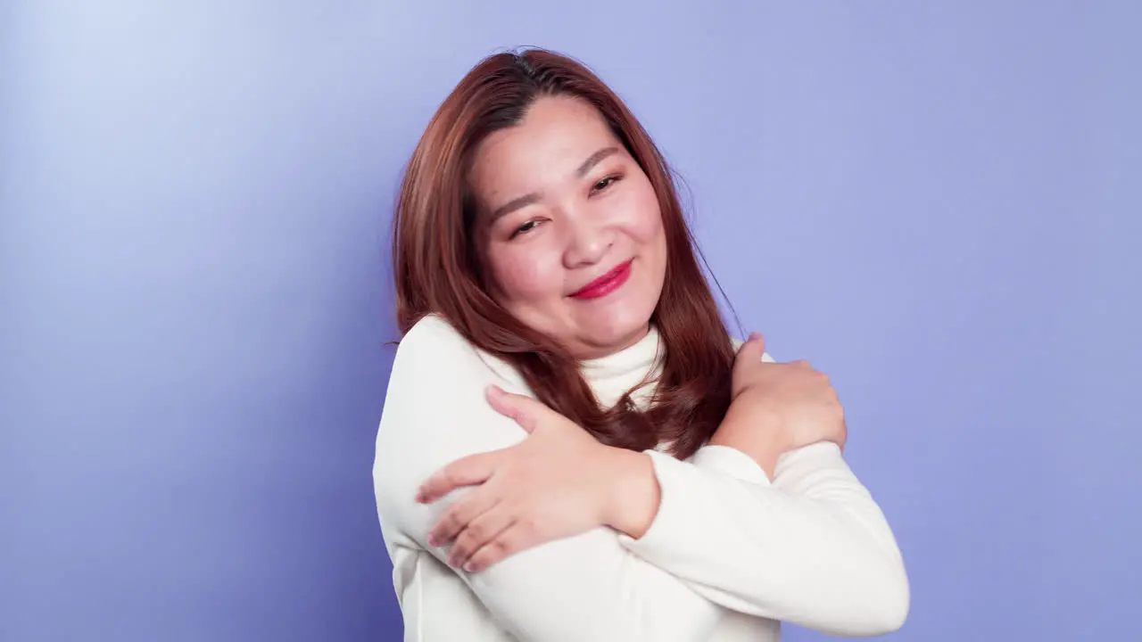 Young beautiful woman feeling in love smiling cuddling and hugging herself being selfish on purple background-2