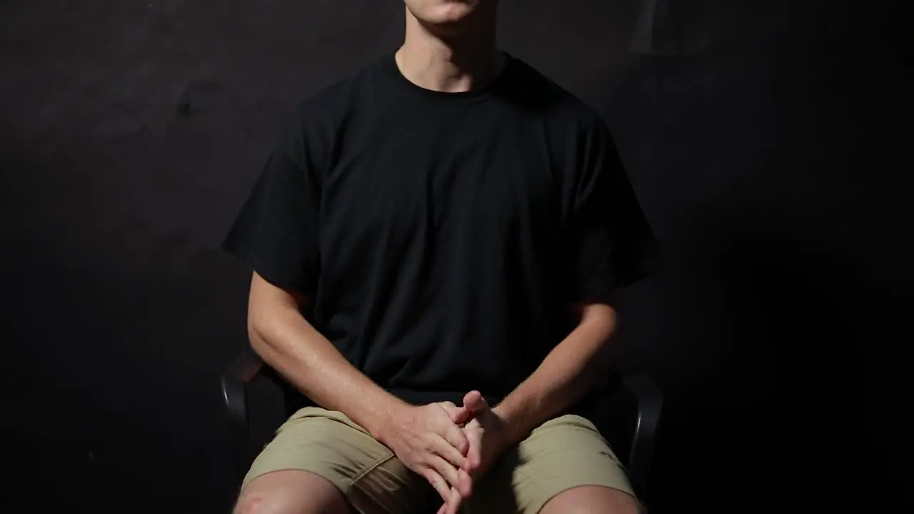 Shot of a man sitting in a chair with his fingers unlocked rubbing his hands together