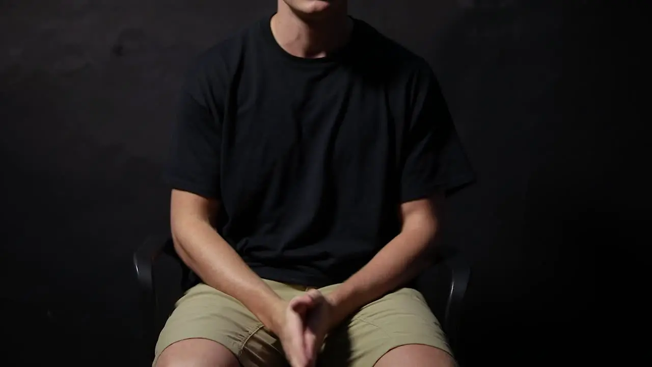 Shot of a man sitting in a chair rubbing his hands together in anxiety