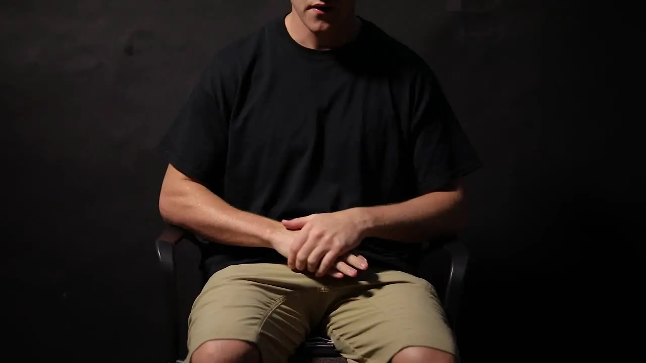 Shot of a man sitting on a chair rubbing his hands together in anxiety