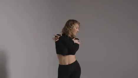 Three Quarter Length Studio Shot Of Young Woman Doing Dance Practise Against Grey Background 1