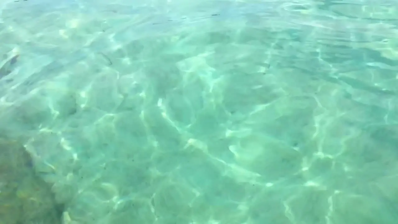 Slow motion of bright crystal clear translucent and transparent sea water surface with white sand floor and ripples