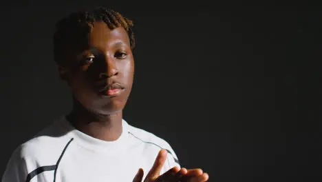 Studio Portrait Of Young Male Footballer Wearing Club Kit Ready For Game