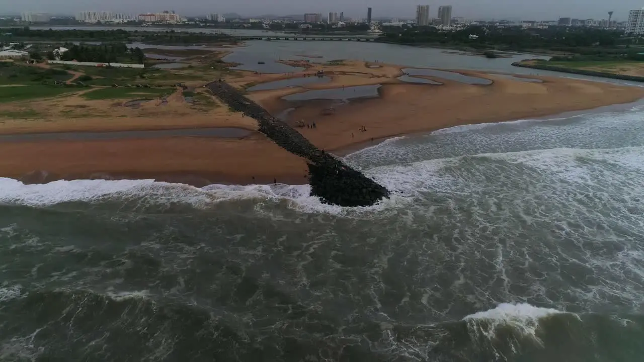 PEOPLE Hold Indian national flag on a rocky beach front with waves crashing Drone flies down towards them