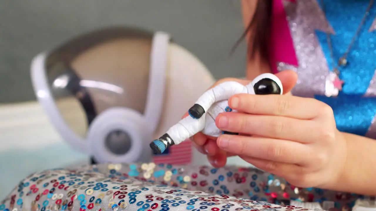 Girl playing with an astronaut toy and having fun with the cosmonaut figurine hands close up