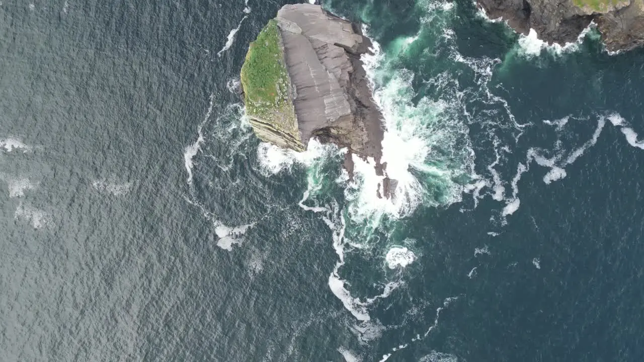 Aerial view cliff meeting the turbulent sea waves crashing against the shore