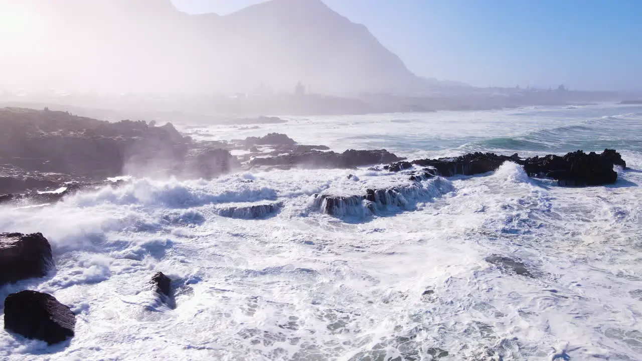 Incessant waves pounding rocky coastline with morning mist at sunrise