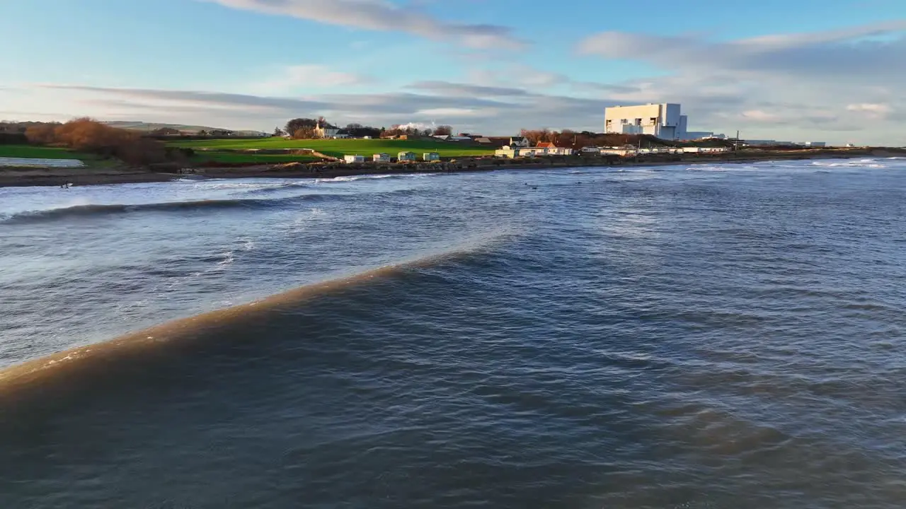 Evening Tide Low Aerial of Waves and Surfers and the Sunset Glow at Thorntonloch Beach Scottish Coast Dunbar Scotland United Kingdom