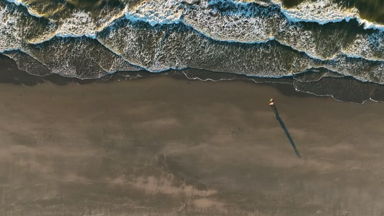 Beautiful Cinematic Drone Shot of Couple Walking on The Beach During Sunset