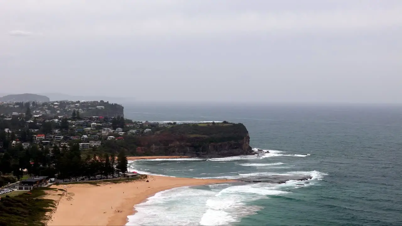 Overcast day at a coastal cliffside and beach community Waves washing ashore on a sandy beach