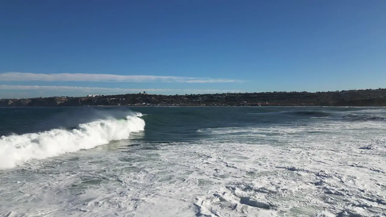 4K Slow motion footage of large ocean waves crashing on cliffs at high tide in La Jolla Cove in San Diego Californiaas a pelican flys by