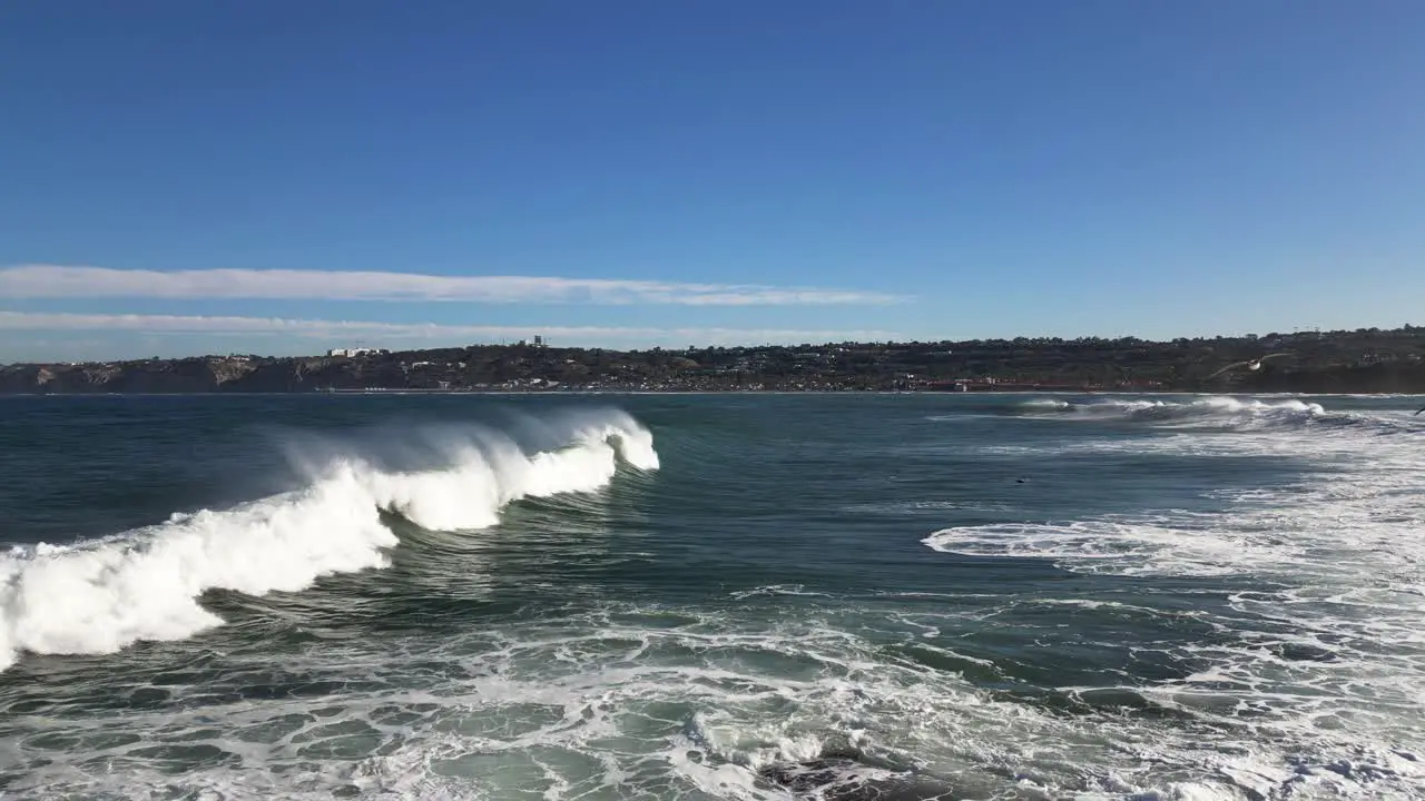 4K Slow motion footage of large ocean waves crashing on cliffs at high tide in La Jolla Cove in San Diego California as a pelicans fly by