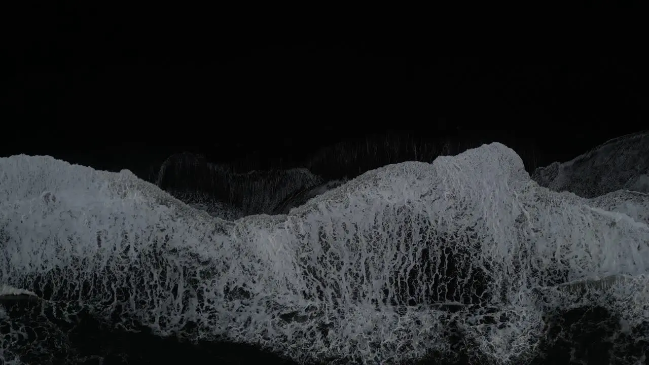 Top down of waves crashing on the south coast of Iceland with black sands aerial