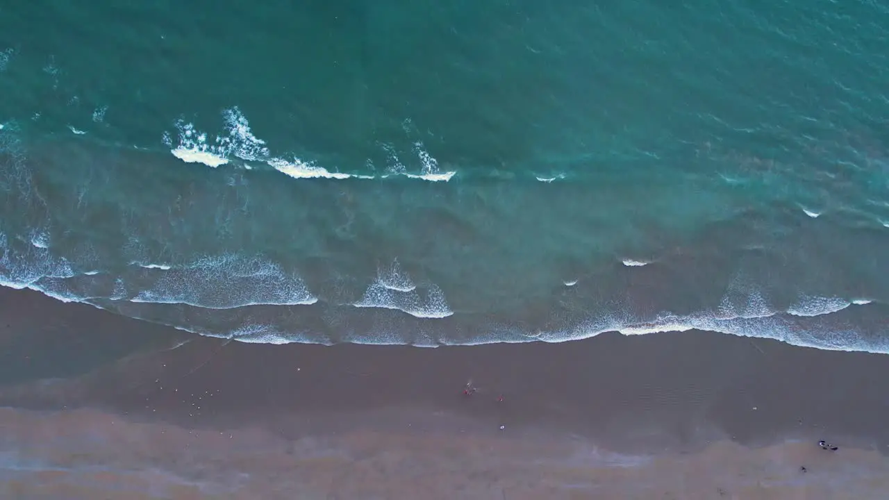 Aerial view of gentle waves hitting a sandy beach from the top view