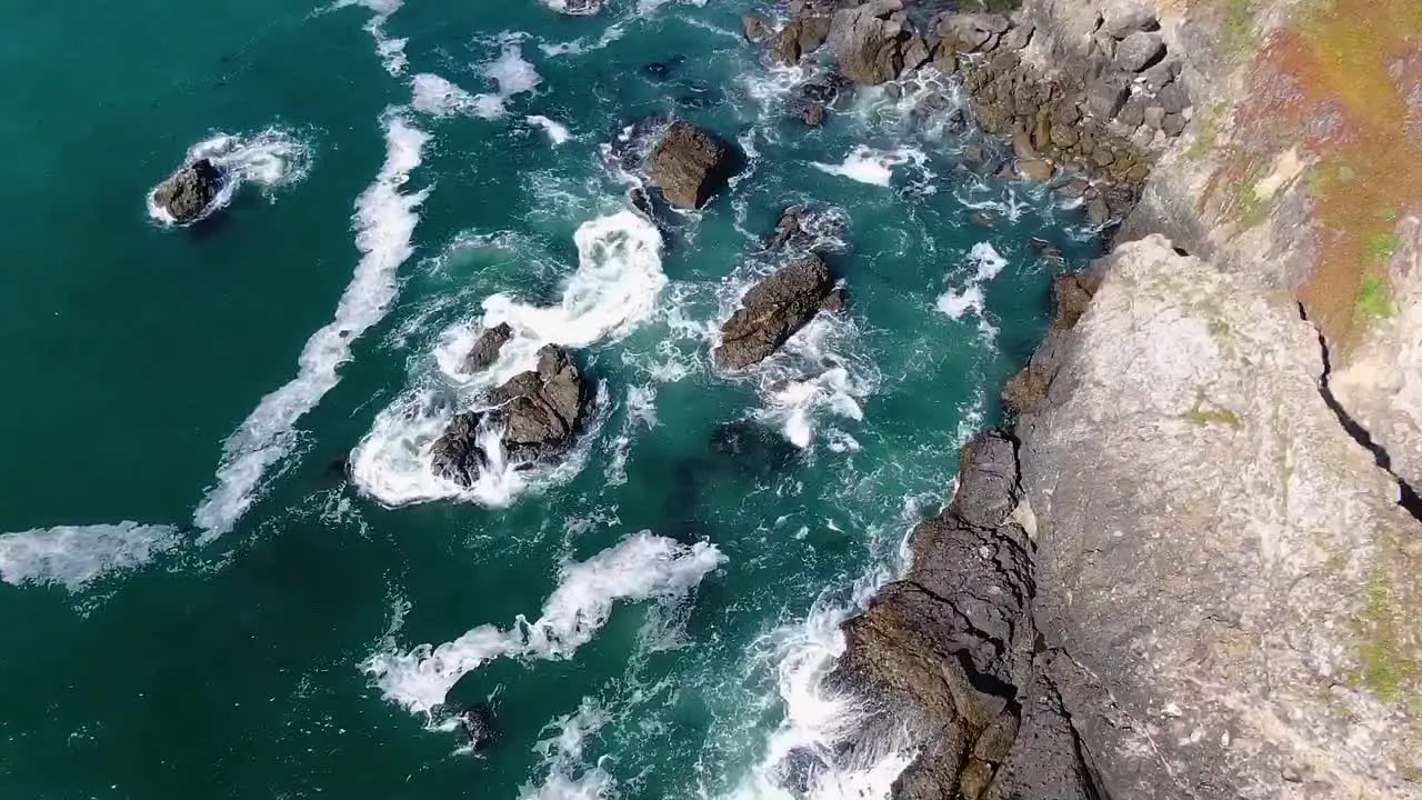 Aerial top-view video capturing the beauty of a blue rocky coast with waves gently crashing against a rugged shoreline in Bodega Bay Gualala Coast California