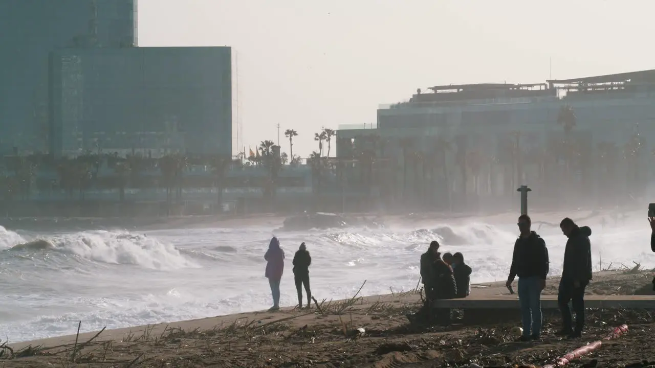 60FPS Huge waves crash on the beach in Barcelona after a devastating storm people take pictures zoomed shot