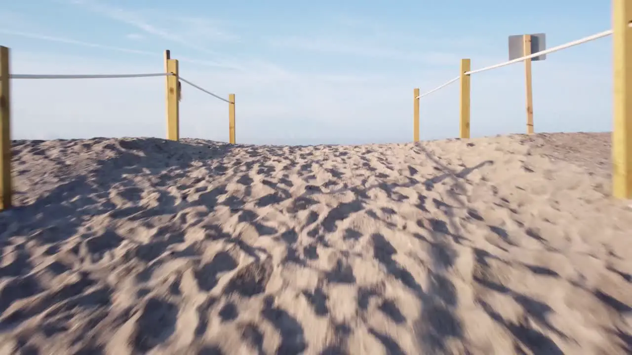 Drone flies over a sand dune at the beach to reveal the waves