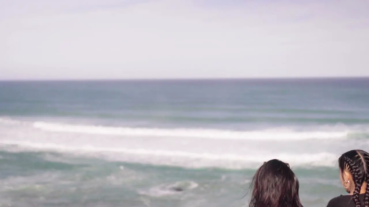 Two females looking out towards ocean tides arriving on shore along Great Ocean Road Victoria Australia