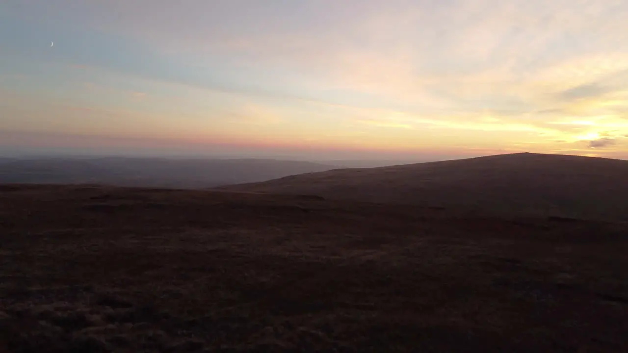 A 4K Aerial Drone Shot Rising Over Brecon Beacons During Sunset with a Crescent Moon