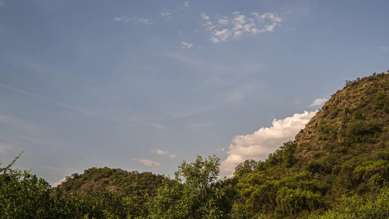 Time lapse shot of rising moon at blue sky during flying clouds at sunset Moving plants and green mountains lighting by sun in Cordoba Argentina