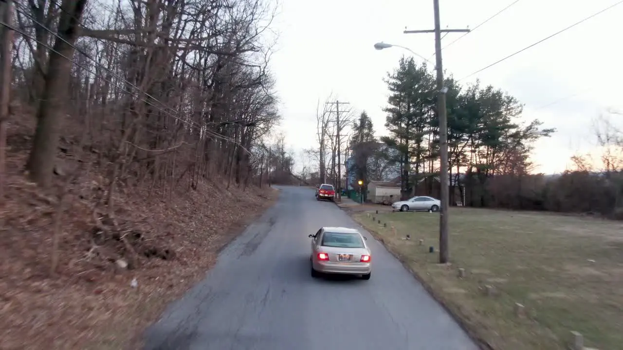 Aerial tracking shot of brown car going up hill during winter