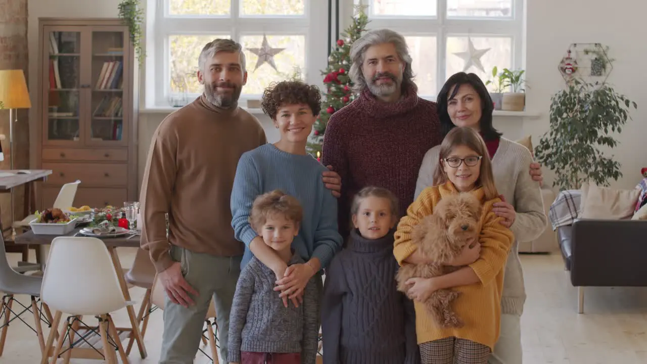 Smiling Family Looking At Camera In Living Room With Table And Christmas Decorations