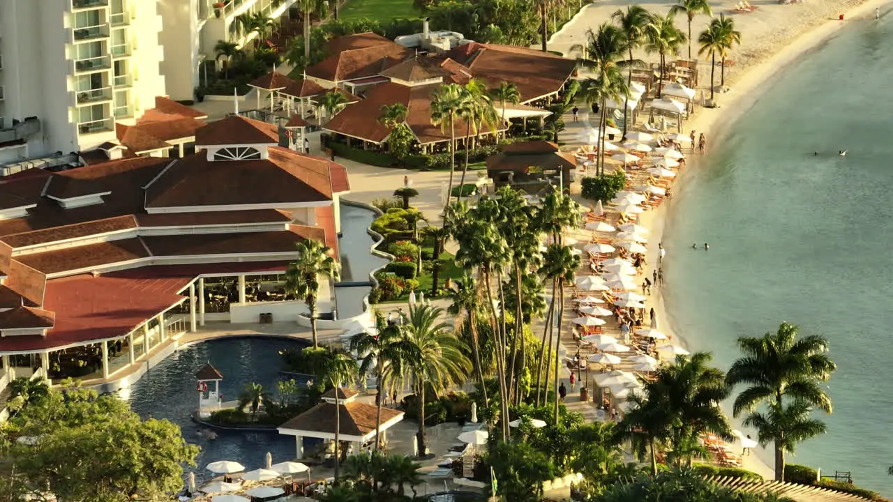 Luxury resort aerial pan of the beach and pool while the sunsets over the Jamaican ocean