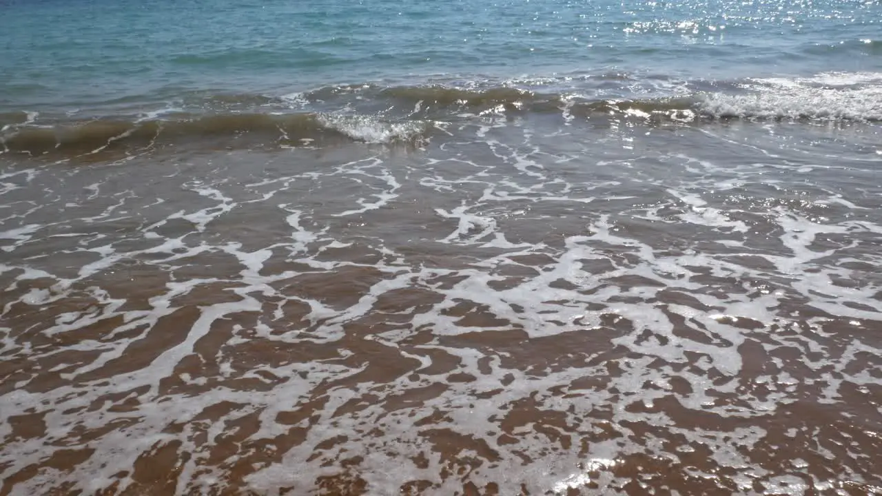 Beautiful calm waves over the brown sand of Lakkos Beach on a perfect sunny day