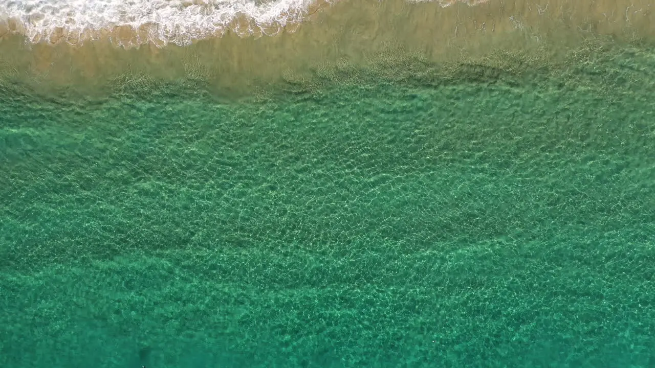 4k Drone zoom out shot of blue turquoise ocean sea by the beach shore at Byron Bay Australia