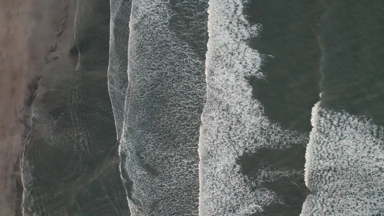 Static bird's eye view of waves breaking gently on Iceland shoreline