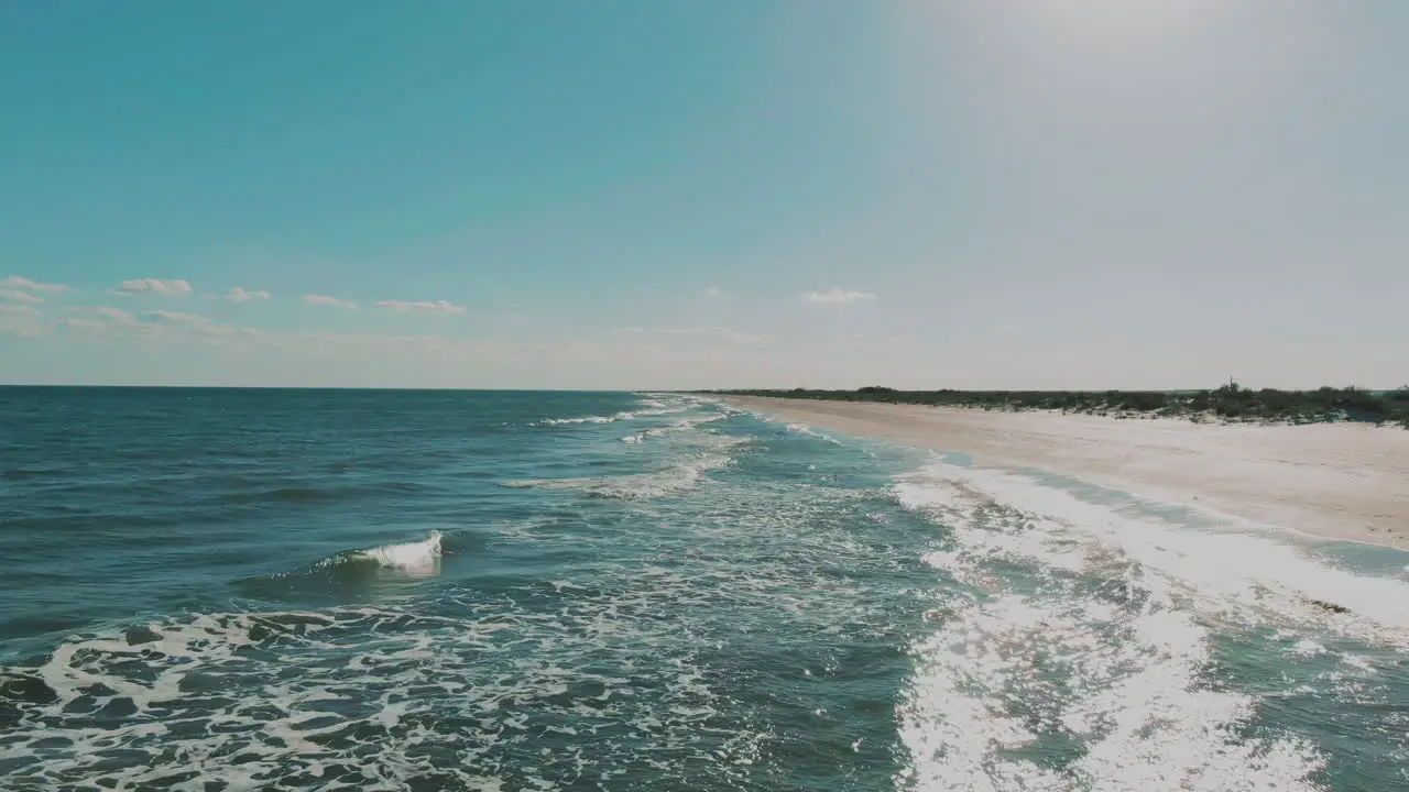 Low altitude drone shot with the sea and the beach transitioning into a high altitude shot sunny clear warm day