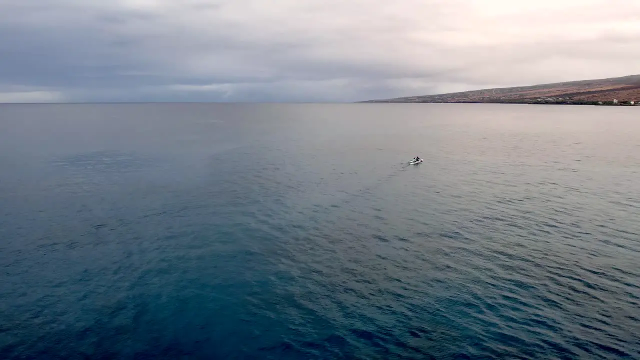 Two-person ocean kayak paddling along calm waters towards the distant shore aerial orbiting parallax view