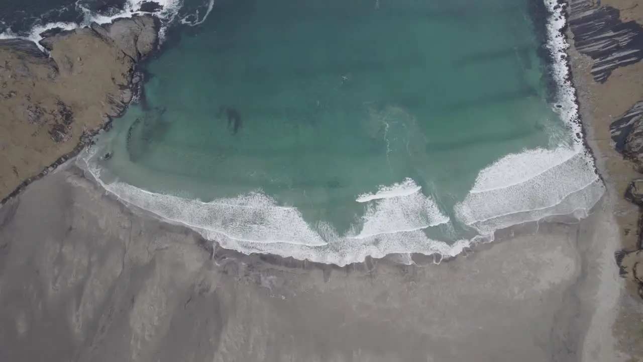 Aerial view above waves at the Bunes beach in gloomy Lofoten Norway top down drone shot