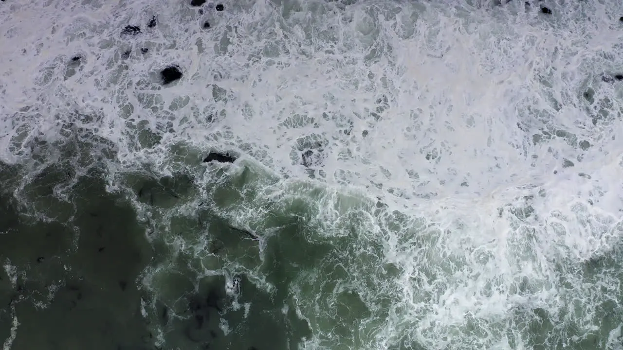 Texture of white foam swirls in grey ocean waves Aerial Top Down Shot