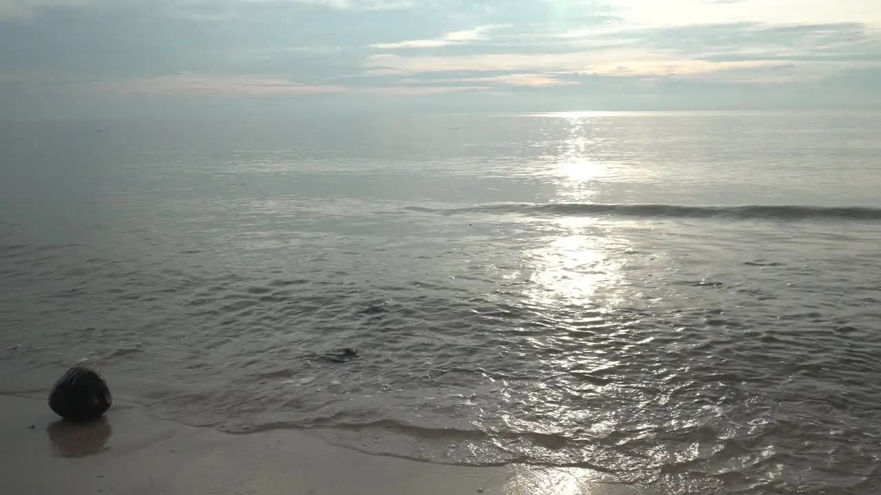 Close up shot of a dramatic morning sunrise the golden rays reflecting of the ocean water as the shallow waves wash up on the sandy beach of Cha Am Phetchaburi Thailand