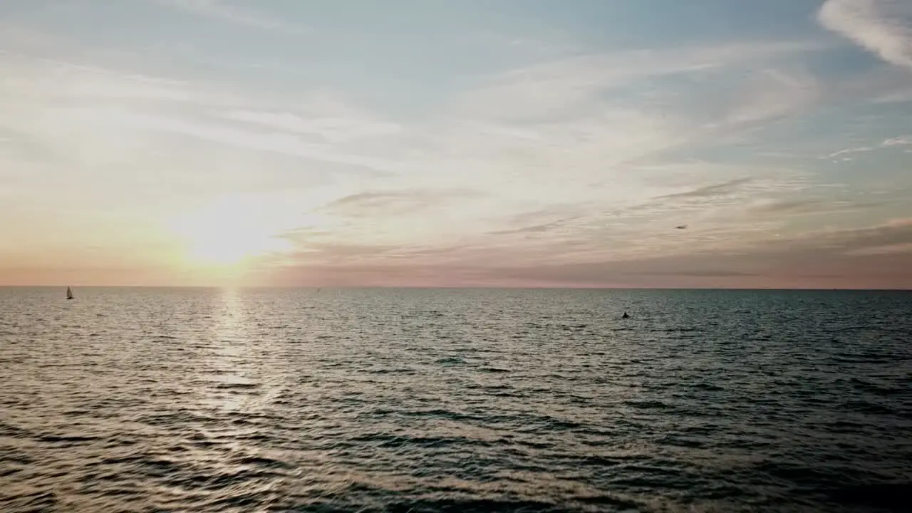 Drone flies close to water towards sun