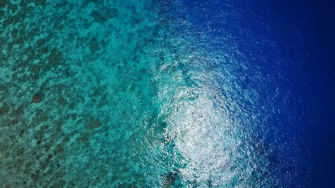 Shallow to deep blue water on reef fall off into depths birds eyes view rotating shot