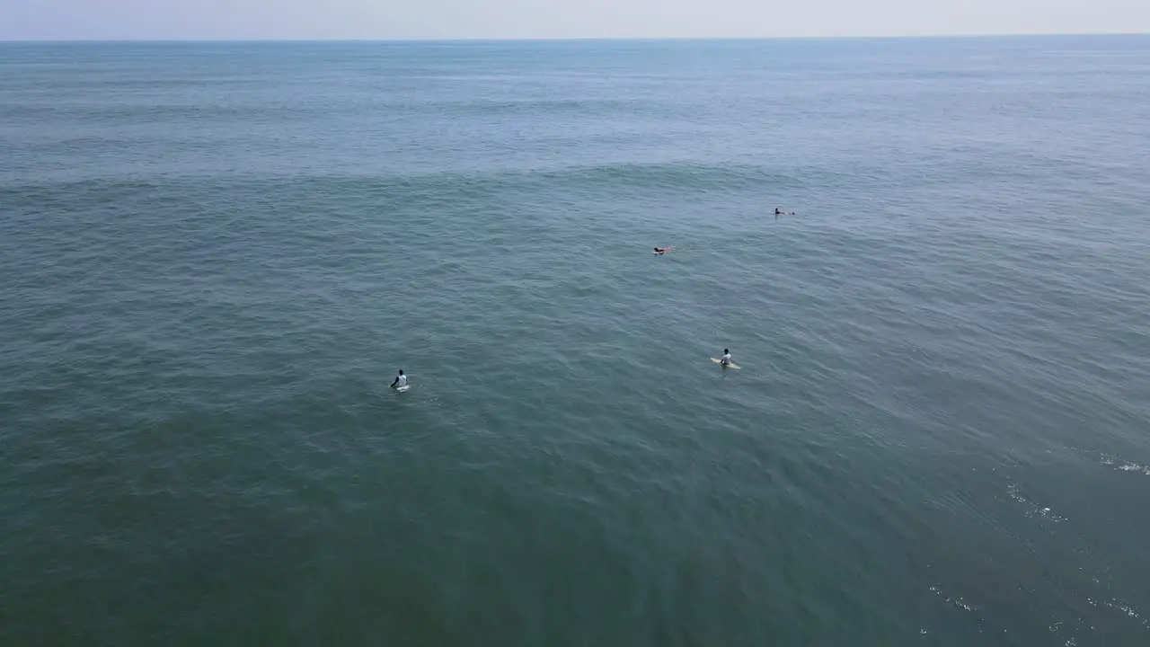 Aerial view full shot surfers waiting for the waves on the bitcoin beach in El Salvador Mexico blue sky and sunny day in the background