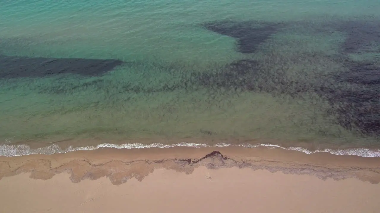 Medium sideways flight right above sand at Kalogria beach with view of ocean spotted dark bottom Greece aerial