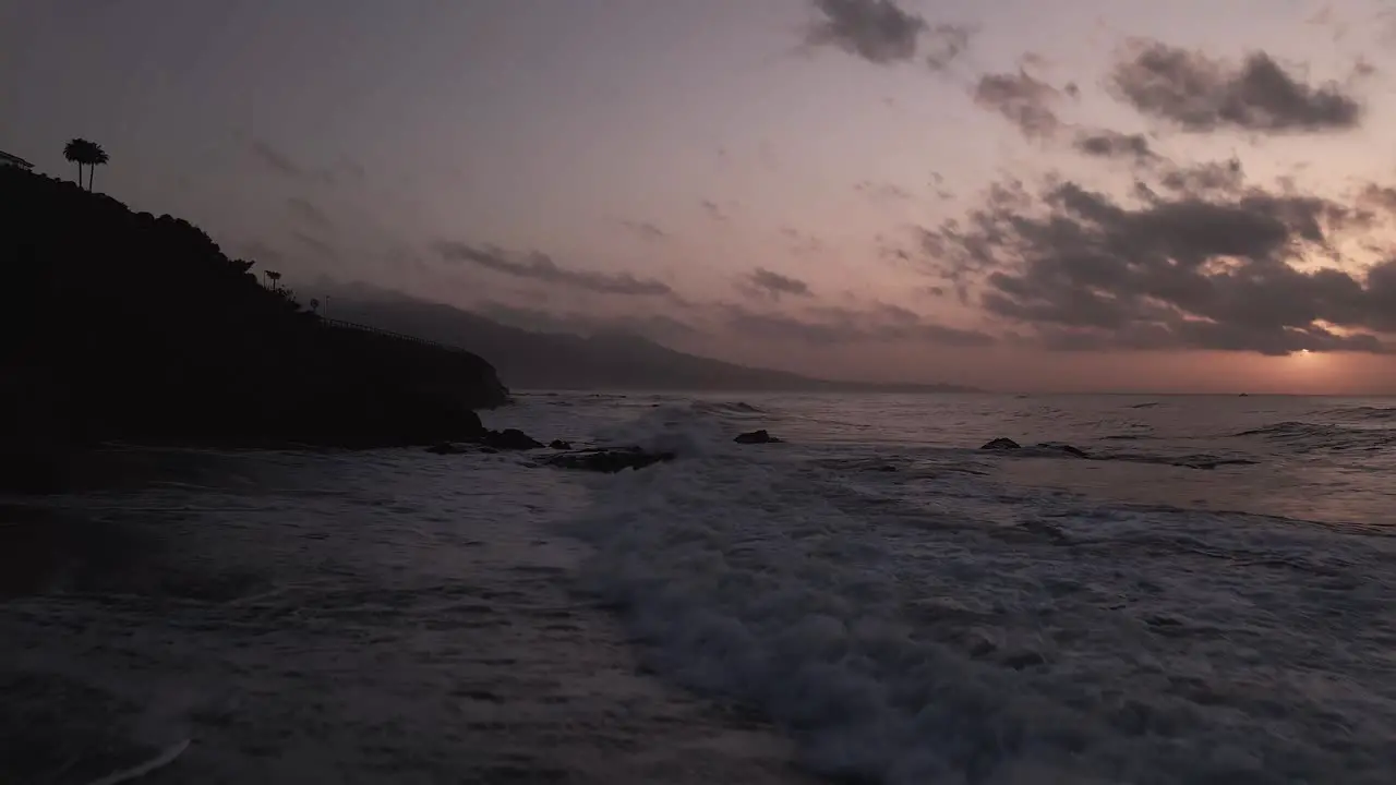 Aerial view flying down mountain range dramatic sunset coastal beach seascape horizon