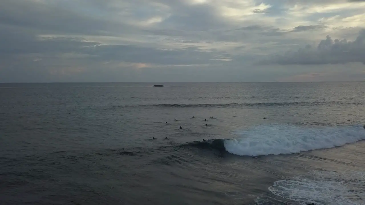 Surfers ride shore break wave at dusk low