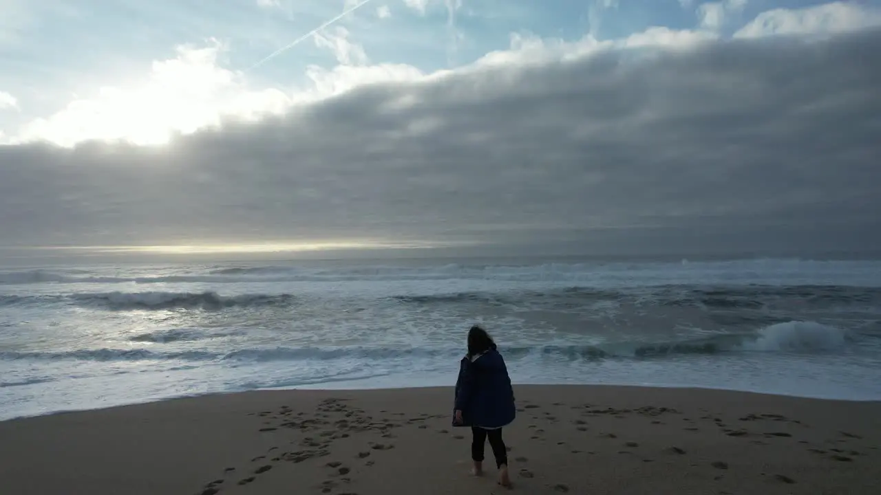 Young Girl on the Beach at Winter Day with Storm Clouds in the Sky